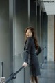 A woman in a business suit leaning against a railing.