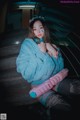 A woman in a blue fur coat sitting on some stairs.