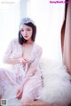 A woman in a white lingerie sitting on a bed.