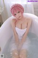A woman with pink hair sitting in a bathtub.