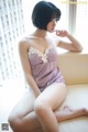 A woman sitting on a window sill in a purple lingerie.