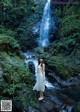 A woman standing in front of a waterfall.